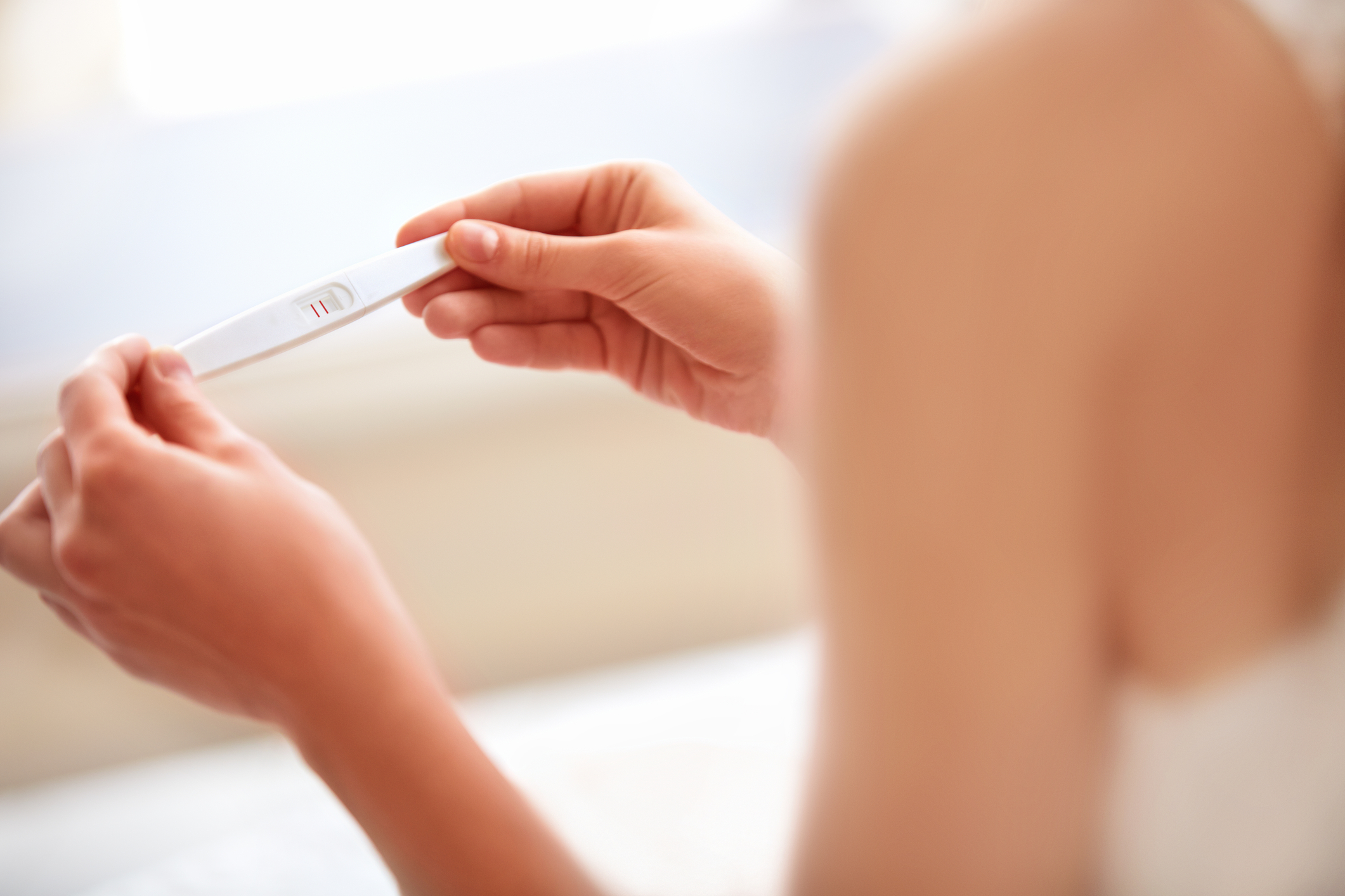 Une femme tient un test de grossesse positif dans ses mains.